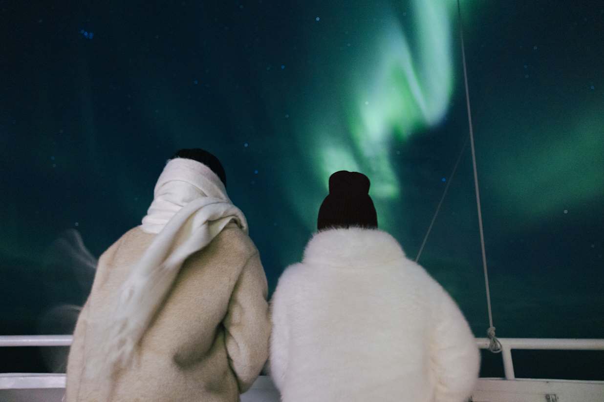 Two female travellers on a cruise ship watching the northern lights